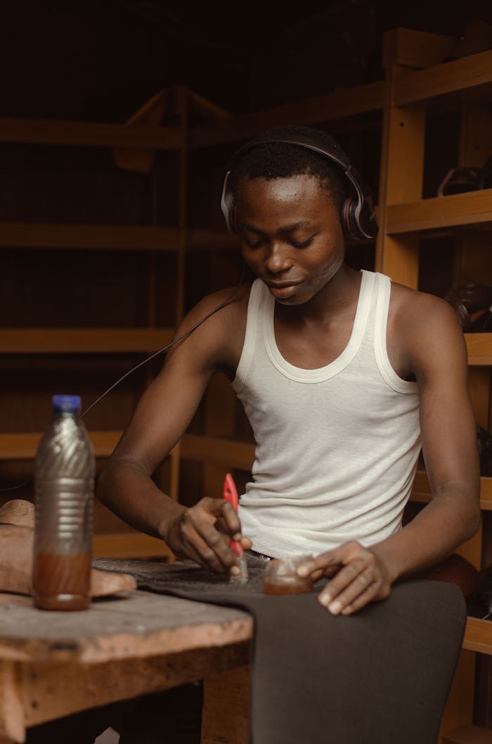 Portrait of a young artisan working and listening to music indoors in Nigeria.