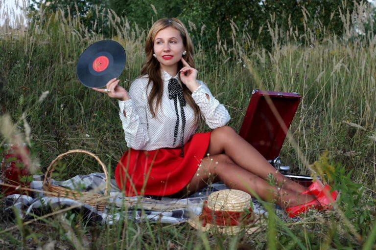 A woman enjoys a vintage picnic holding a vinyl record in a meadow setting.